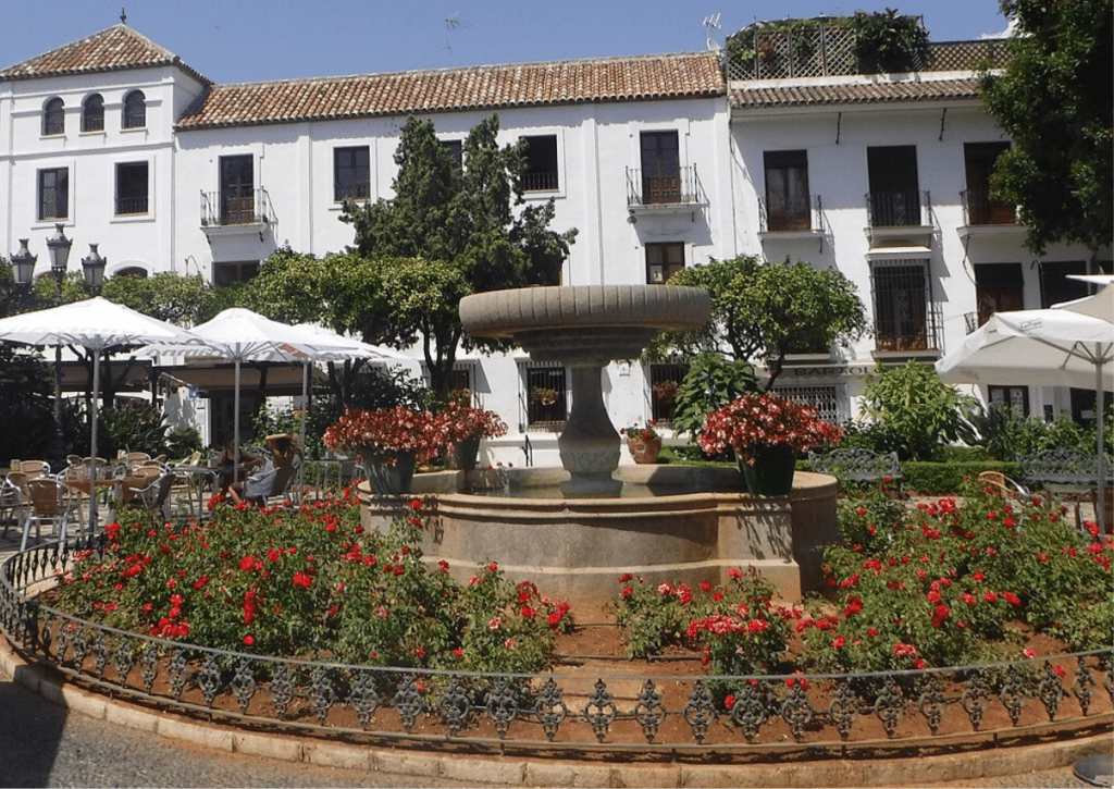 Plaza de las Flores in Estepona with orange trees, flowers, and café terraces.