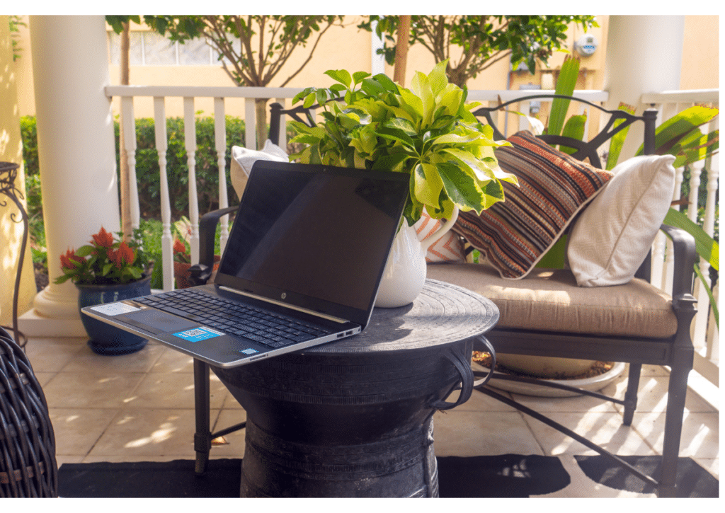 Outdoor workspace with a laptop on a table surrounded by plant