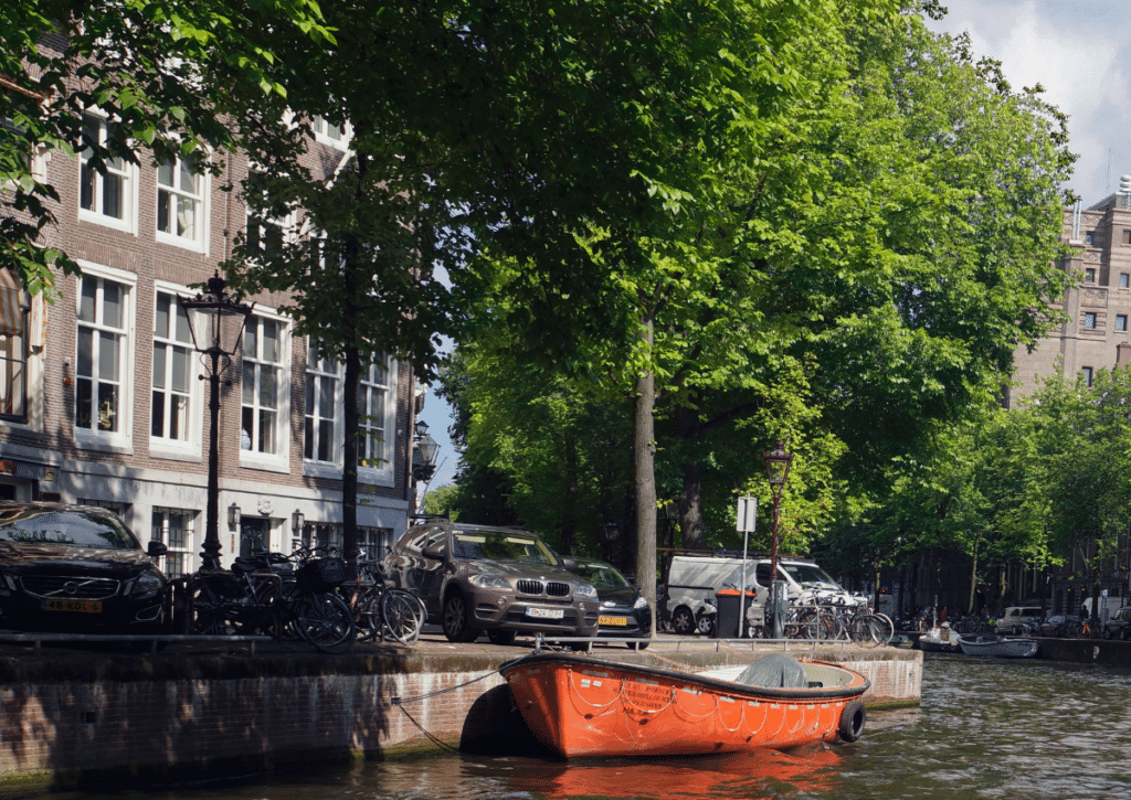 Golden Bend in Amsterdam with canal, bicycles, cars, and historic canal houses showing three modes of transportation.