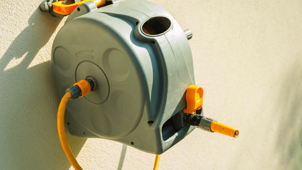Wall‑mounted retractable garden hose reel with a clean pull‑and‑rewind design attached to an exterior wall.